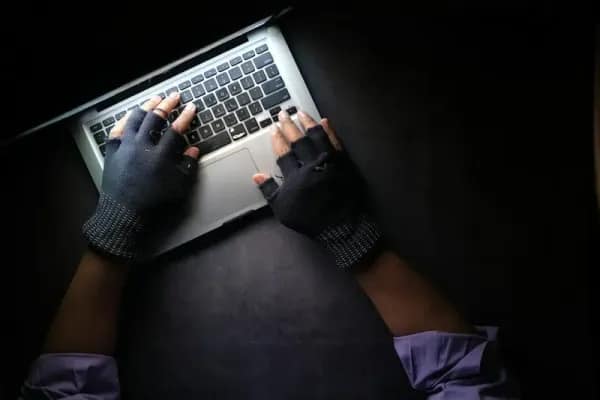 Assicurazione Cyber - mani con guanti senza dita su notebook